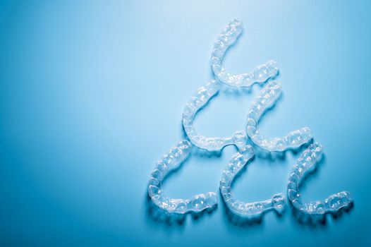 transparent straighteners for teeth in the shape of a pyramid on a blue background, dentistry and orthodontics. 3D printing in modern medicine.