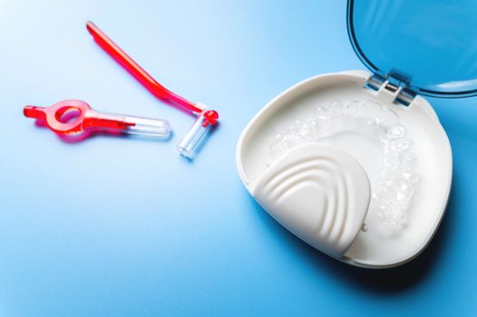 close-up, white box with plastic braces inside and red interdental brush. orthodontic care and cosmetology.