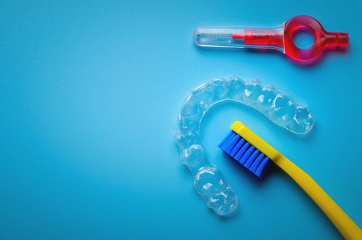 toothbrush with transparent plastic aligners and interdental brush on blue background, dental clinic banner.