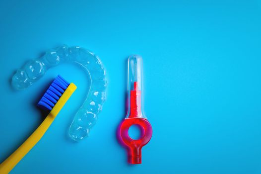 toothbrush with transparent plastic aligners and interdental brush on blue background, dental clinic banner.