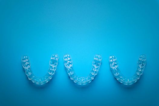 a row of aligners, side view, on a blue background.