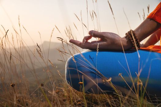 close-up, woman's hand in the lotus position in the grass in the mountains, meditation and relaxation.