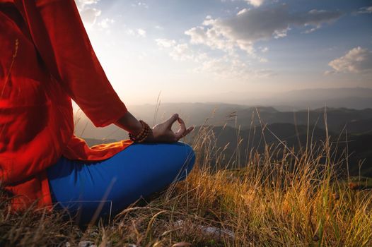 close-up, woman's hand in the lotus position in the grass in the mountains, meditation and relaxation.