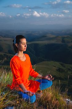 young yogi woman practicing meditation with closed eyes in lotus position at sunset.