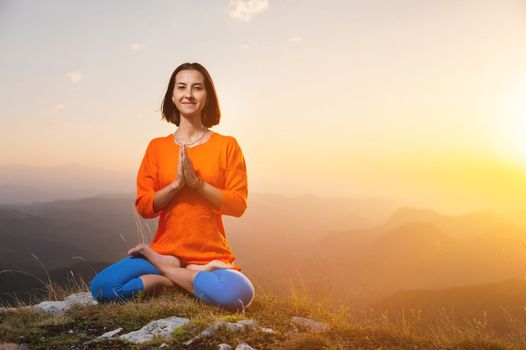 woman doing yoga and meditation in the mountains at sunset, rest at the end of the day.