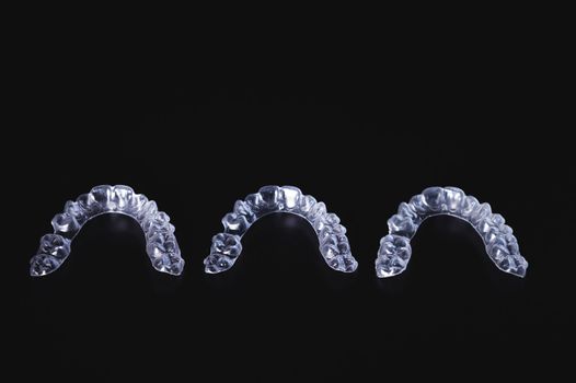 a row of aligners on a black background. modern transparent braces, new care in orthodontics.