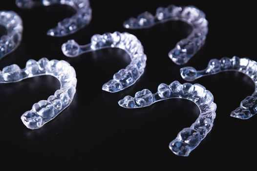 a lot of aligners lie on a black background, studio shot.