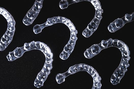 a lot of aligners lie on a black background, studio shot.