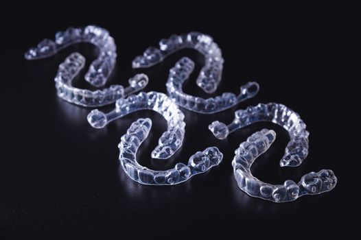 a lot of aligners lie on a black background, studio shot.