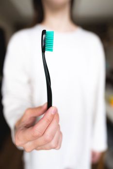 Woman holding a toothbrush in the foreground in focus, blurred background. Oral hygiene.