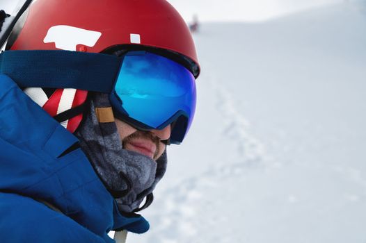 male athlete in a snowboard helmet and ski goggles looks into the distance, profile portrait.
