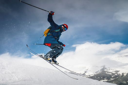 male skier jumping from mountain creating snow plume, winter extreme sport, downhill skiing.