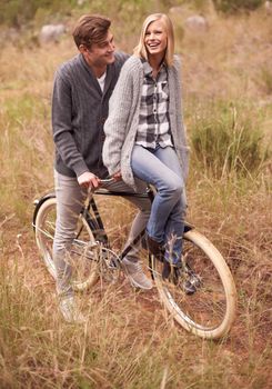 Playful and in love. A young couple enjoying a bike ride outdoors together