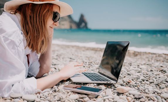 Woman sea laptop. Business woman in yellow hat working on laptop by sea. Close up on hands of pretty lady typing on computer outdoors summer day. Freelance, digital nomad, travel and holidays concept