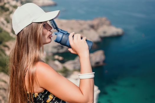 Woman travel sea. Happy tourist taking picture outdoors for memories. Woman traveler looks at the edge of the cliff on the sea bay of mountains, sharing travel adventure journey.