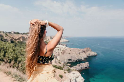 Woman travel sea. Happy tourist taking picture outdoors for memories. Woman traveler looks at the edge of the cliff on the sea bay of mountains, sharing travel adventure journey.