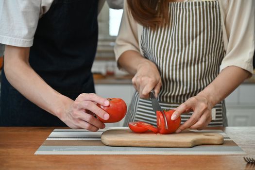Cropped image of young couple preparing ingredient for making healthy salad in kitchen.