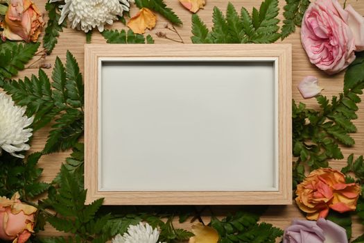 Empty wooden frame surrounded by fresh flowers ,floral frame, spring or summer background.