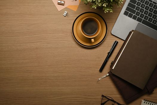 Top view of wooden working with laptop, books, glasses and coffee cup. Copy space for your text.