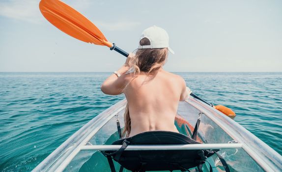 Woman in kayak back view. Happy young woman with long hair floating in transparent kayak on the crystal clear sea. Summer holiday vacation and cheerful female people having fun on the boat.