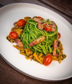 Recipe for spaghetti with spinach cream and smoked bacon, tomatoes and chanterelle mushrooms. High quality photo