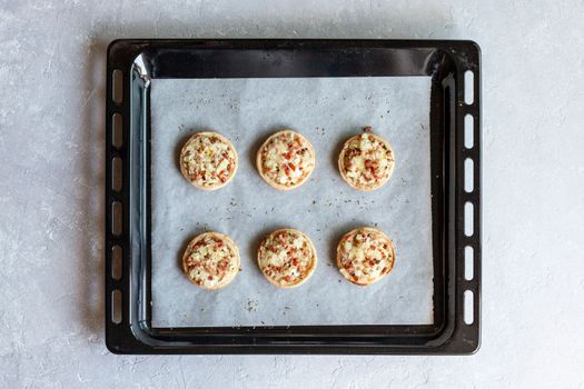 mini Flammekueche, or tarte flambee, french specialty, on the paper on the oven-tray