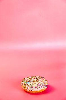 Sweet donuts stacked in a stack on a pink background. Copy space, various glaze and sprinkels chocolate chip, snack fast food sweets concept candy