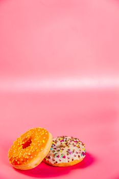Sweet donuts stacked in a stack on a pink background. Copy space, various glaze and sprinkels chocolate chip, snack fast food sweets concept candy