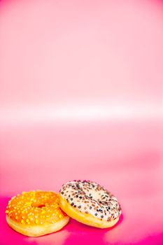 Sweet donuts stacked in a stack on a pink background. Copy space, various glaze and sprinkels chocolate chip, snack fast food sweets concept candy