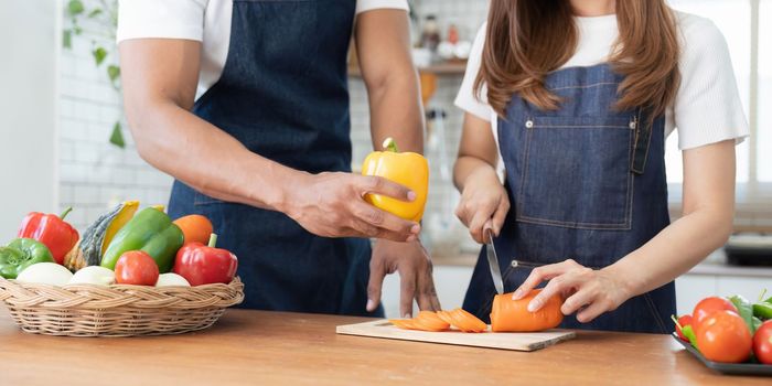 Happy couple preparing food together in kitchen at home ready to cook together.