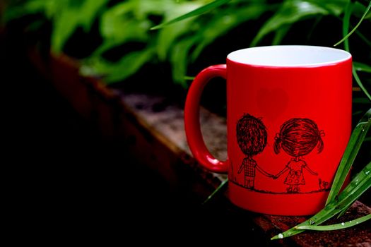 a small bowl-shaped container for drinking from, typically having a handle. Red cup with a drawn couple in love in a greenhouse with space for text.