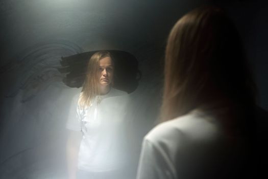 Blond woman in the reflection of sweaty mirror. Female in white t-shirt staring at herself with blank look. Age crisis