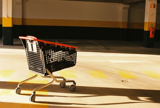 Modern shopping trolley with red handle and black walls in the parking zone of supermarket