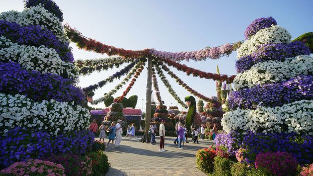 Hanging garlands of fresh flowers in a city park with visitors