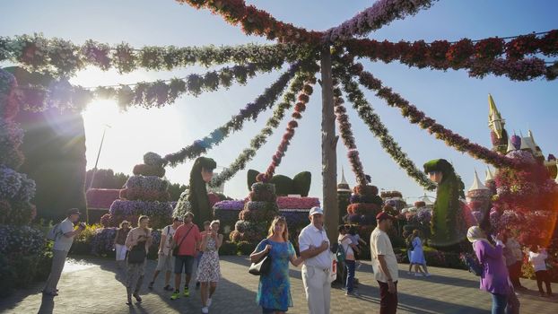 Hanging garlands of fresh flowers in a city park with visitors