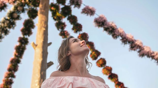 Girl on the background of hanging daisies of fresh flowers in a city park in Dubai