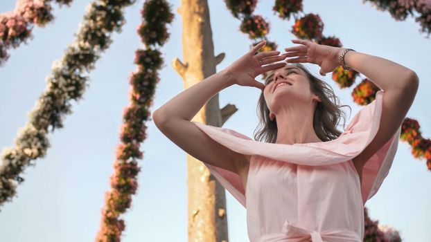 Girl on the background of hanging daisies of fresh flowers in a city park