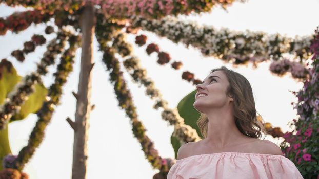 Girl on the background of hanging daisies of fresh flowers in a city park