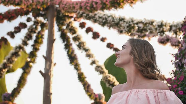 Girl on the background of hanging daisies of fresh flowers in a city park
