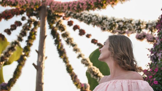 Girl on the background of hanging daisies of fresh flowers in a city park in Dubai