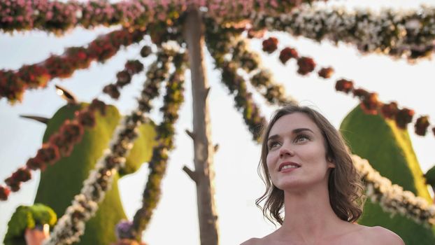 Girl on the background of hanging daisies of fresh flowers in a city park