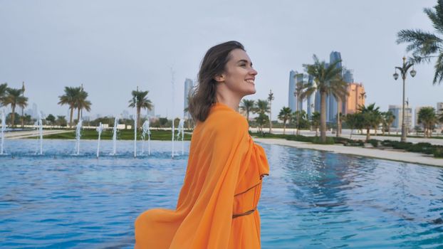A girl in an orange dress walks through the evening Abu Dhabi. UAE