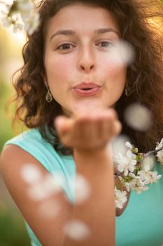 A young brunette girl poses with a blossoming cherry branch.