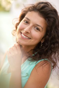 A young brunette girl poses with a blossoming cherry branch.