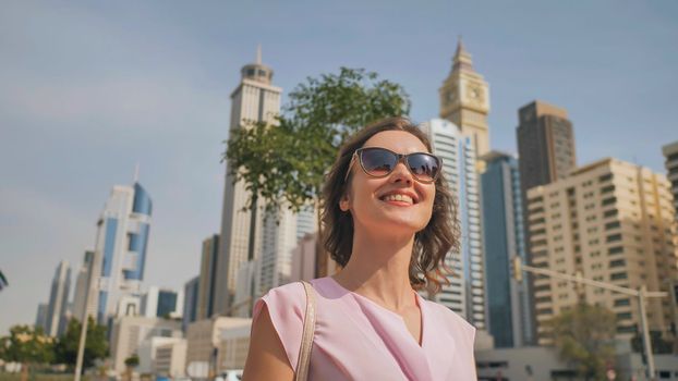 Happy girl walks in the center of Dubai against the background of skyscrapers