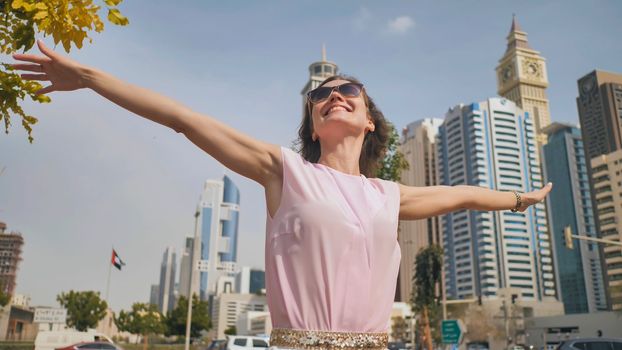 Happy girl walks in the center of Dubai against the background of skyscrapers
