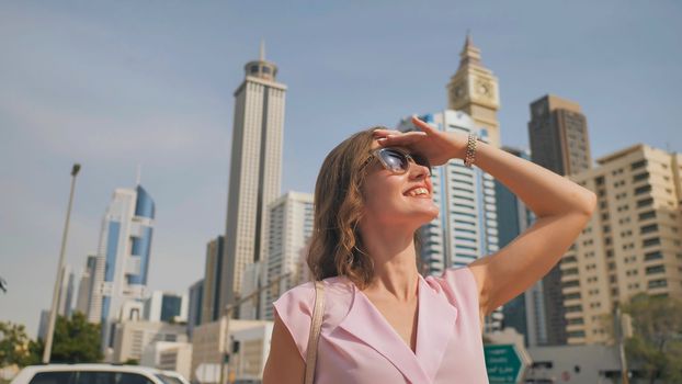 Happy girl walks in the center of Dubai against the background of skyscrapers