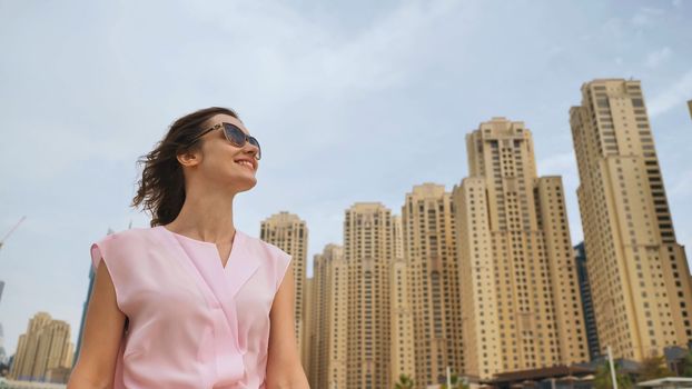 Happy girl walks in the center of Dubai against the background of skyscrapers