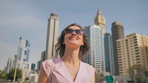 Happy girl walks in the center of Dubai against the background of skyscrapers