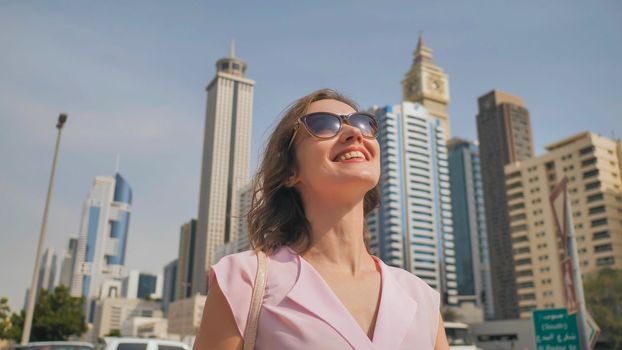 Happy girl walks in the center of Dubai against the background of skyscrapers